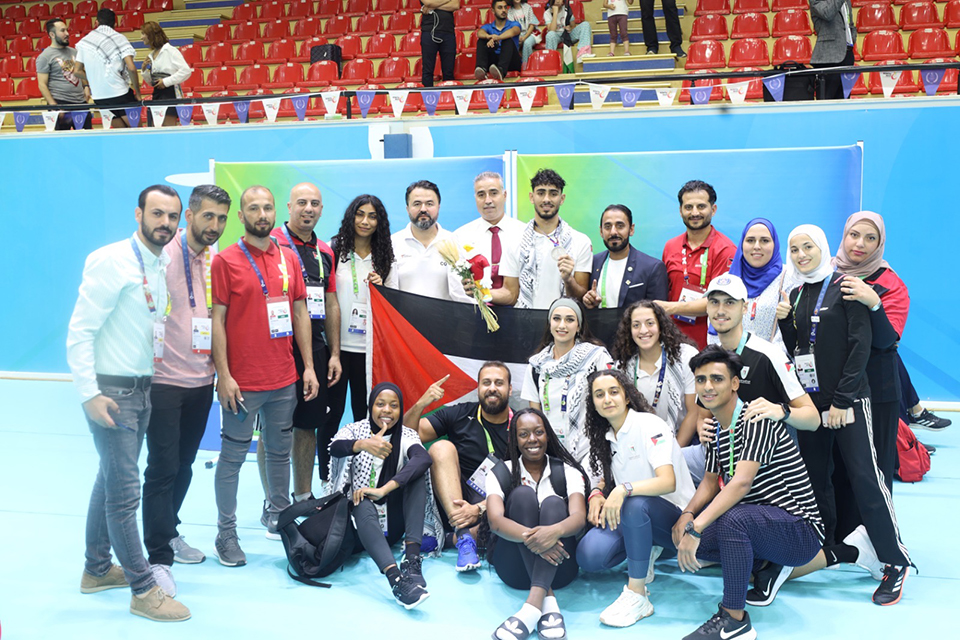 A group of people posing in various ways in a sports hall.