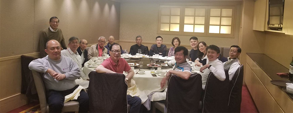 Patrick Lee pictured seated at a table at a monthly Hong Kong alumni dinner with a group of fellow alumni.