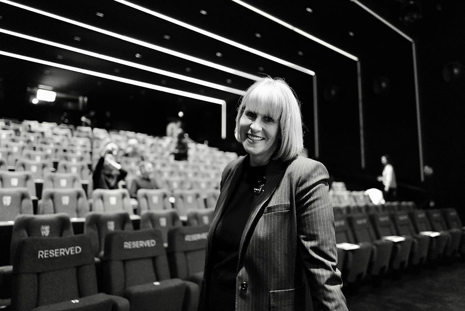 Sue Anstiss standing in front of seats in a theatre.