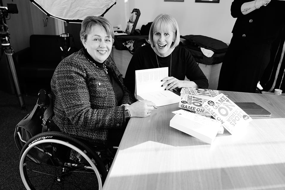 Baroness Grey-Thompson and Sue Anstiss smiling at the camera. There are copies of Sue’s Game On book on the table.