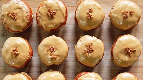 An image of many doughnuts with topping lined up in a line.