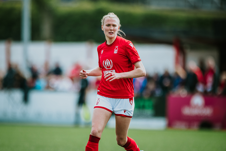 Charlotte Greengrass on the pitch in red and white football strip. Image: Ami Ford 