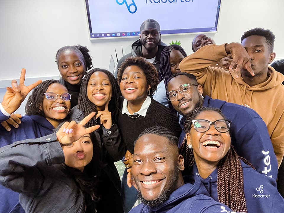 Twelve people posing in front of a whiteboard.