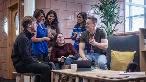 Members of LUinc. standing and sitting together around a laptop