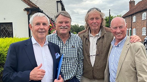 Four people standing together smiling