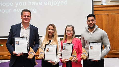 The four distinguished alumni award winners standing together, holding their certificates