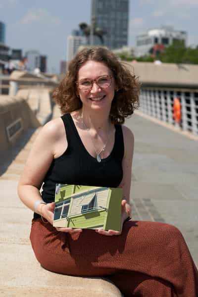 Monica seated outside holding a small painting