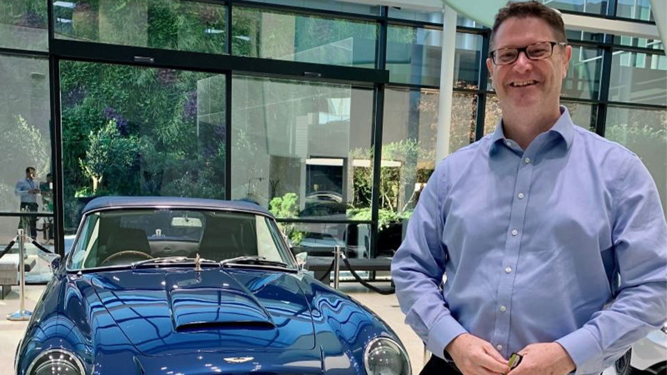 Rob Colmer standing next to a blue car and smiling