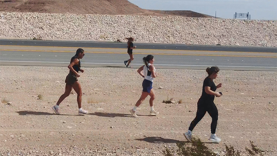 A picture of 4 people running in what looks like a desert