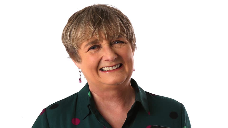 A close up of Christine against a plain white background. She is smiling at the camera.