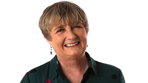 A close up of Christine against a plain white background. She is smiling at the camera.