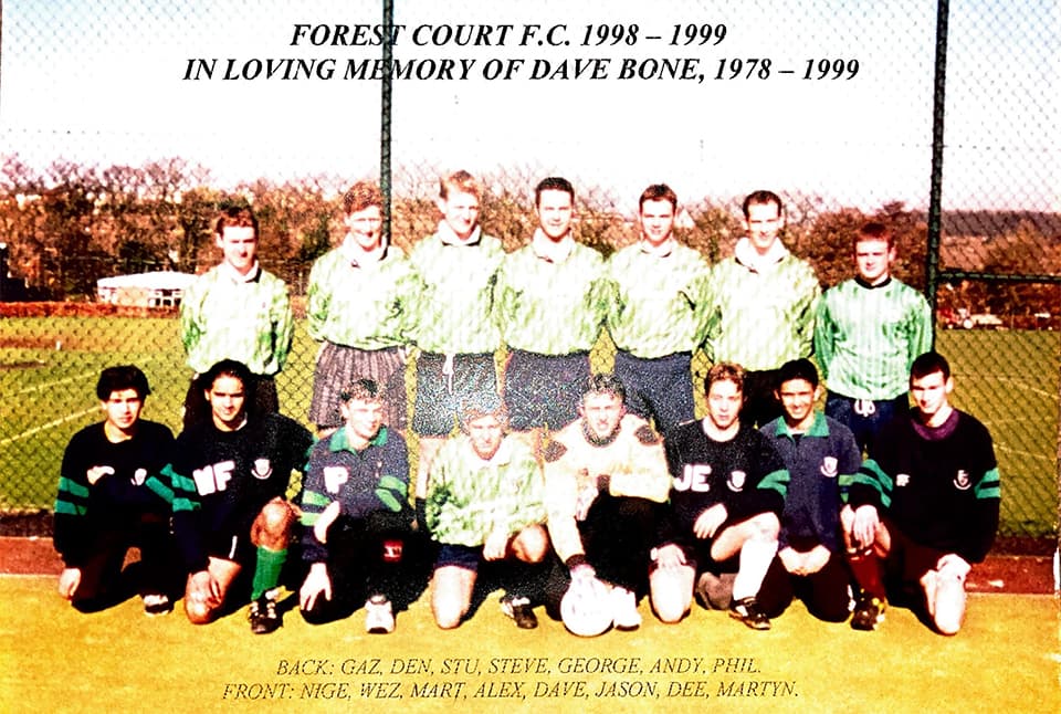 A group of people in football kits. Half stand and half crouch. There is text on the image that reads 