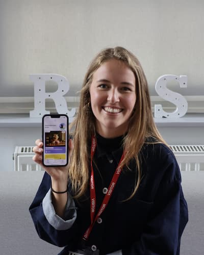 Emily smiling, holding a phone up to show the app