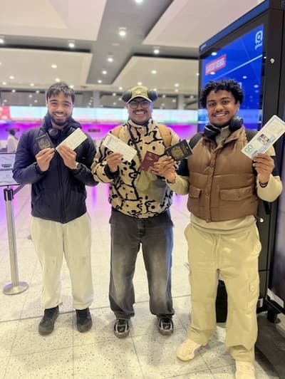 Three people standing, smiling, holding tickets