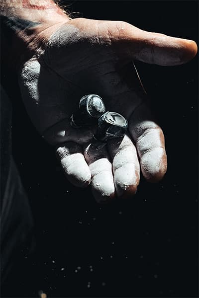 A chalky hand holding the Tzuka earbuds