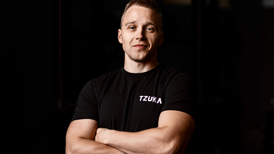 Tom Jelliffe with his arms crossed, wearing a black tshirt, smiling