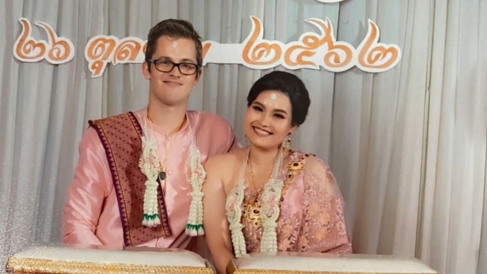 Two people in wedding attire seated and smiling
