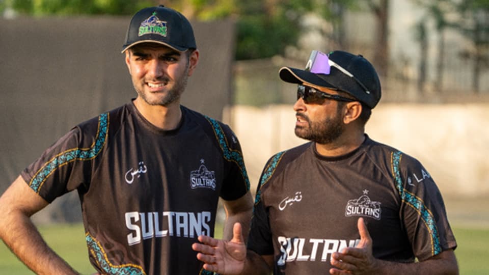 Gohar standing with another person, wearing Sultans tops and caps