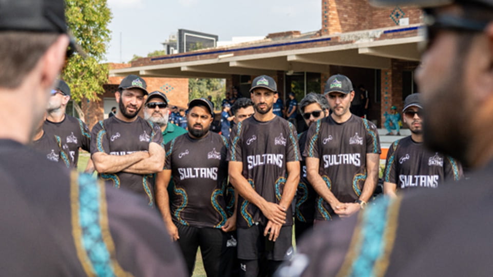 A group of people wearing Sultans tops and caps