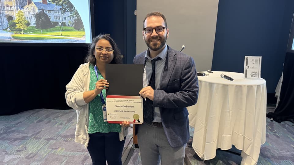 Dr Drakopoulos holding a certificate, standing with someone else