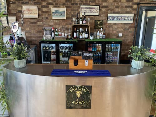 A bar with stocked fridges. A logo is on the front of the bar.