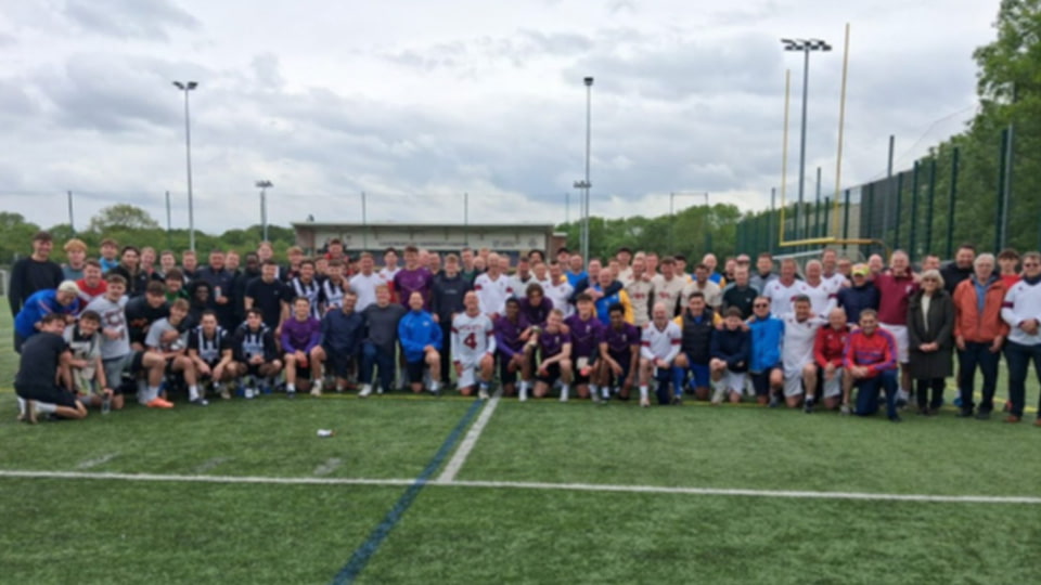 A group of football alumni standing and squatting together on a field