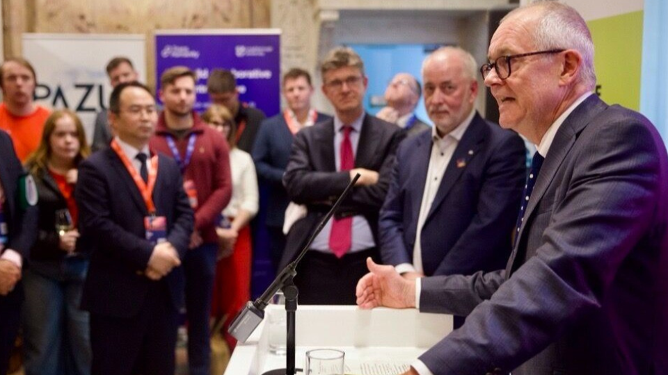 A man speaking at a lectern to an audience.