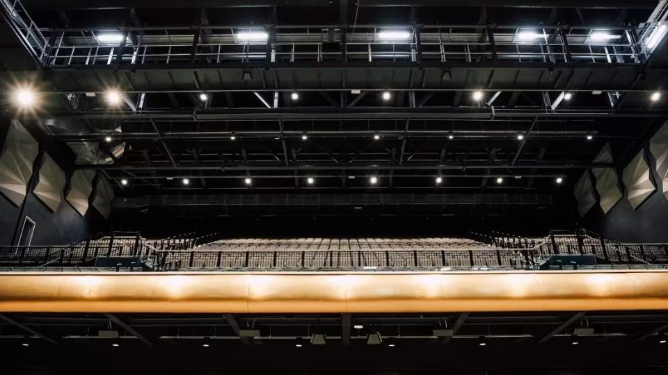 An interior of a darkly lit seating area in a modern theatre.