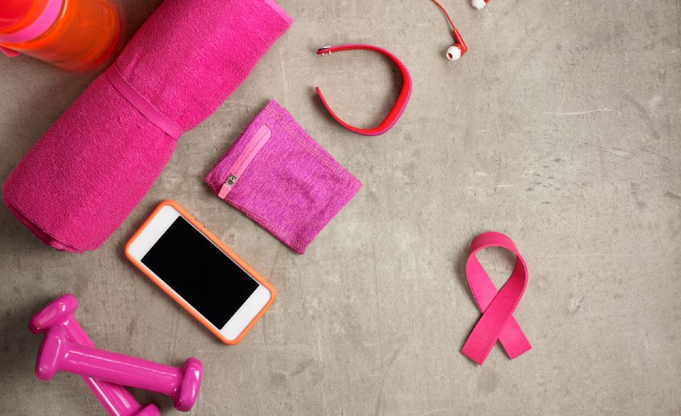 a pink ribbon, phone, hand weights and an exercise mat on the floor