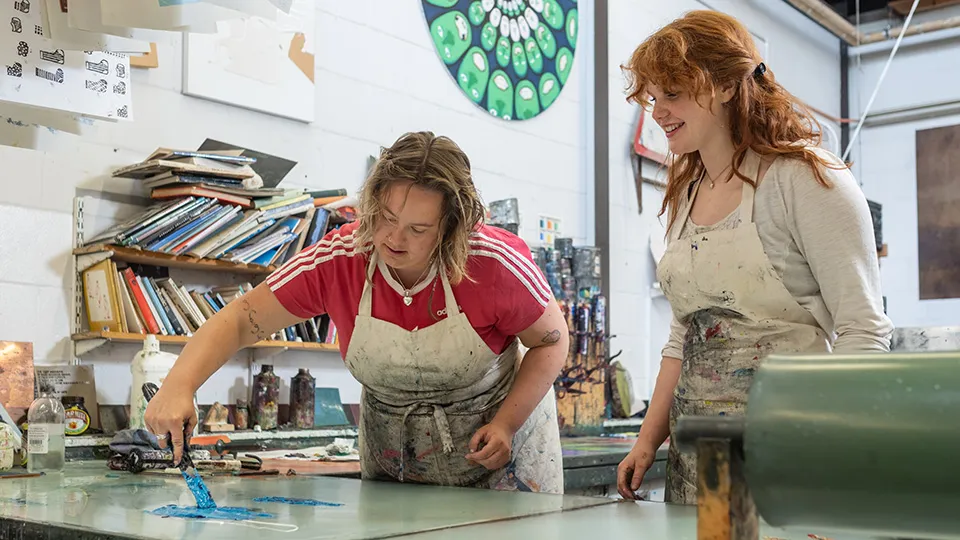 Students working with printmaking ink in a university art studio.