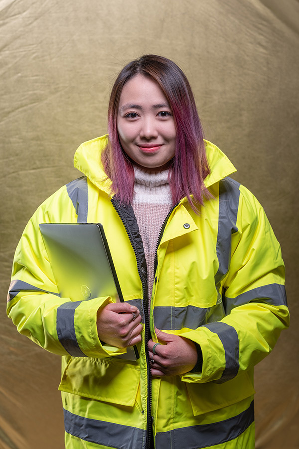 Catherine Yeung wearing a high vis jacket and holding a clip board. 