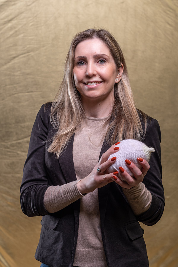 Dr Gemma Witcomb holding a grey knitted boob. 