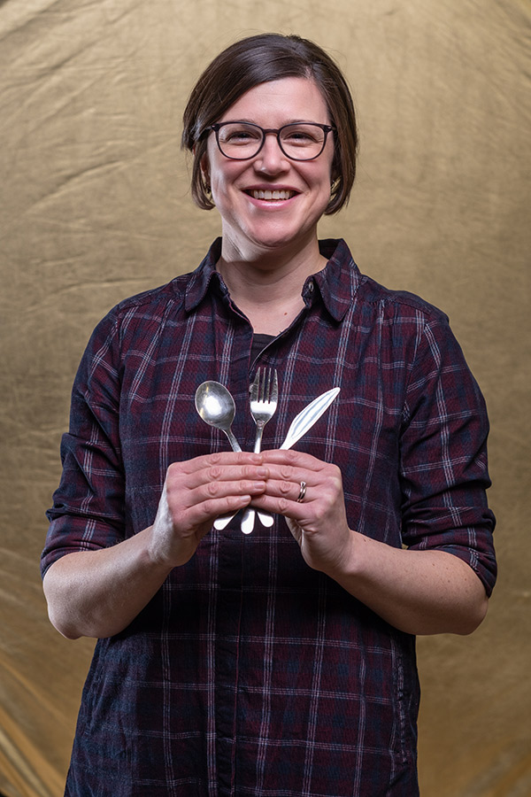 Dr Hannah White with a fan of cutlery in her hands - including a fork, knife and spoon. 