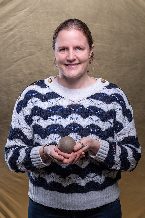 Dr Helen Glanville is stood holding a soil Dorodango ball or “Japanese shiny mud ball” in her hands. 