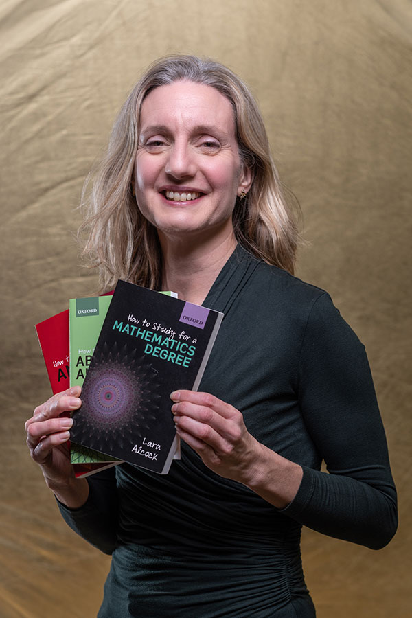 Dr Lara Alcock holding three of her books on mathematics