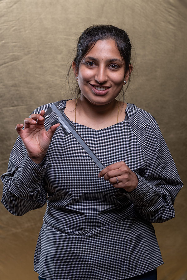 Parvathi Vasudevan stood holding a Vernier caliper, which is a measuring tool.