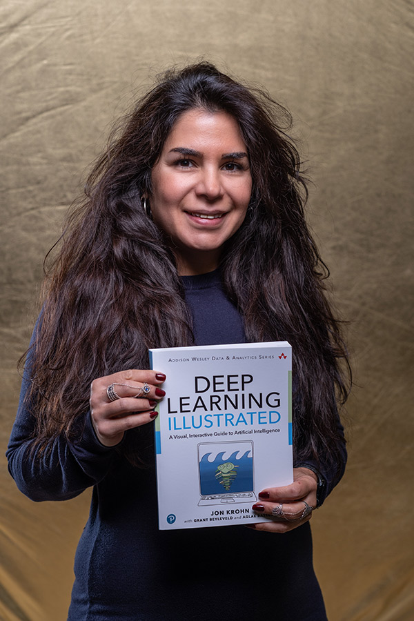Dr Sara Saravi is stood holding a book on Deep Learning which is a branch of Artificial intelligence.