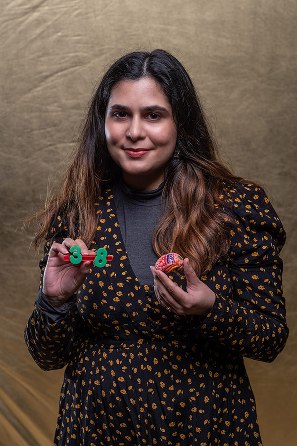 Sheeza Mahak stood holding a small model brain in one hand and the numbers 3 and 8 in the other hand. 