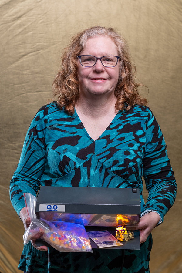 Dr Siân Williams stood holding an Ultra Violet lamp.