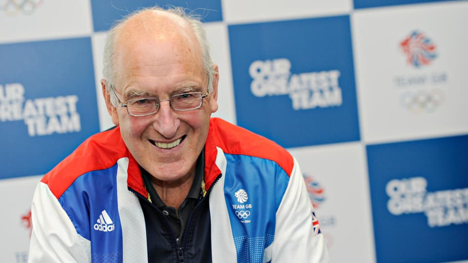 George Gandy smiling, wearing a red white and blue tracksuit top. 