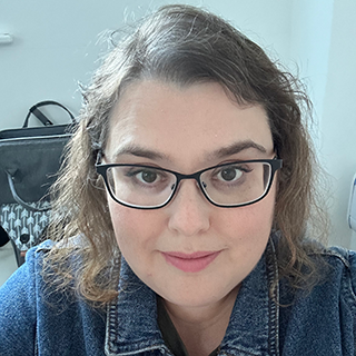 Carly smiling at the camera, wearing glasses