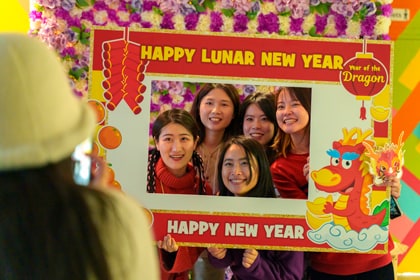 People posing for photo behind Happy Lunar New Year frame