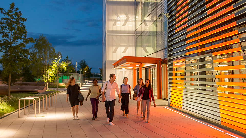 a group of people walking past Loughborough University London building at night