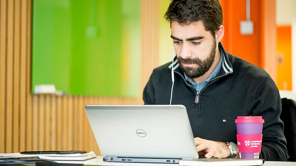 a man wearing headphones uses a laptop computer and has a cup of coffee next to him