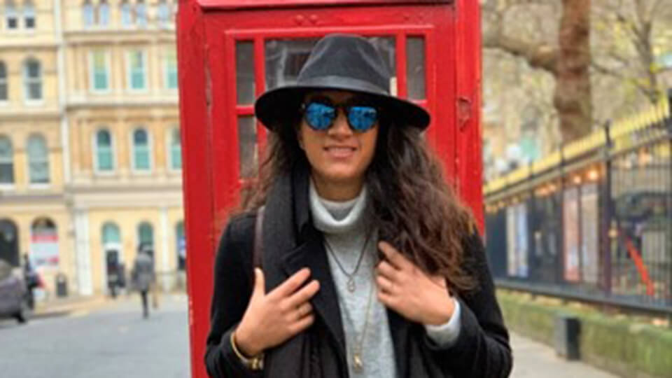Postgraduate student on trip to Birmingham standing in front of red telephone box