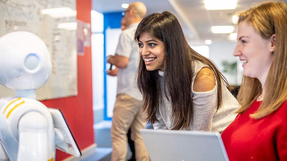 Two female students looking at an AI-powered robot