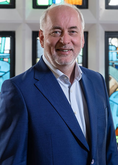 Vice-Chancellor, Nick Jennings standing against a stained glass window
