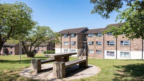 A photograph showing the exterior of Royce Hall accommodation, with a picnic bench in the foreground.