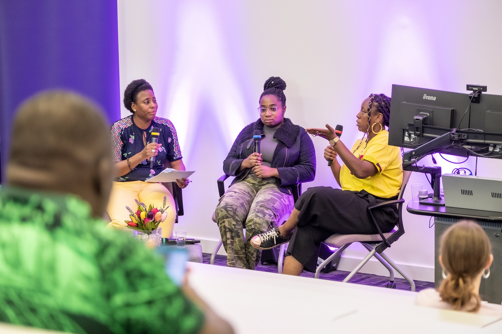 Three black women sit with microphones talking to each other