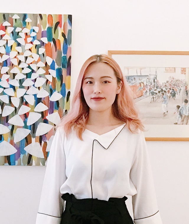 Yajie Hu standing facing the camera in a colorful gallery